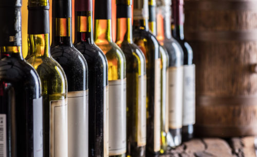 Wine bottles in row and oak wine keg.